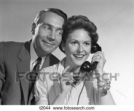 1950S Woman Talking On Phone Smiling Man Leaning In To Listen Indoor View Large Photo Image Picture - 1950S Woman Talking On Phone Smiling Man Leaning In To Listen Indoor . Fotosearch