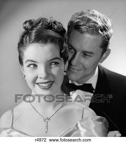 Stock Image - 1960S 1950S Smiling Happy Woman Diamond Necklace Earrings Man Behind Her Wearing Tuxedo Couple Formal Attire Evening Wear . Fotosearch