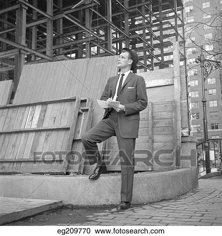 1960S Businessman On Curb Looking Up Into Building Under Construction Writing Notes View Large Photo Image Stock Image - 1960S Businessman On Curb Looking Up Into Building Under Construction Writing Notes. Fotosearch