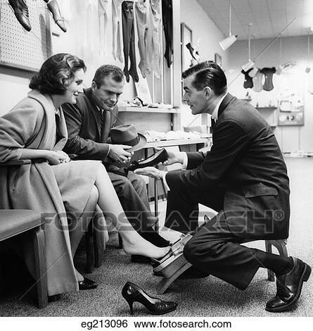 1960S Couple Woman Trying On Shoes Man Looking Impatient Shoe Salesman Kneeling View Large Photo Image Stock Photograph - 1960S Couple Woman Trying On Shoes Man Looking Impatient Shoe Salesman Kneeling. Fotosearch