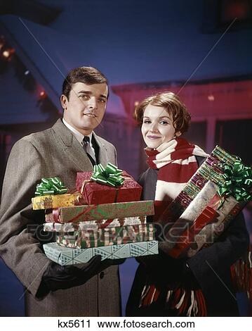 1960 1960S 1970 1970S Couple Man Woman Holding Stock Presents Gifts In Front Of House Decorated With Lights Studio Retro View Large Photo Image Stock Image - 1960 1960S 1970 1970S Couple Man Woman Holding Stock Presents Gifts In Front Of House Decorated With Lights Studio Retro. Fotosearch