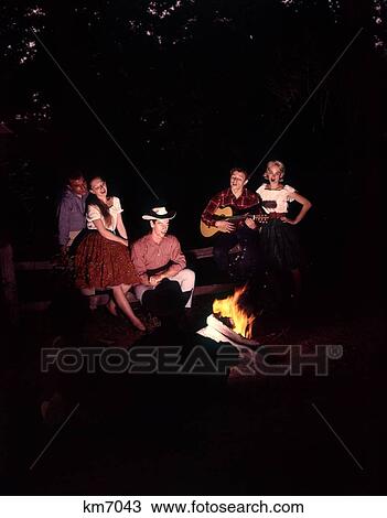 1960 1960S 1970 1970S Couples Men Man Women Woman Sitting Singing Around Campfire Night Country Western View Large Photo Image Stock Image - 1960 1960S 1970 1970S Couples Men Man Women Woman Sitting Singing Around Campfire Night Country Western . Fotosearch