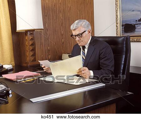1960 1960S 1970 1970S Mature Man Silver Gray Grey Hair Executive Seated Desk Reading Business Papers Men Executives View Large Photo Image Stock Image - 1960 1960S 1970 1970S Mature Man Silver Gray Grey Hair Executive Seated Desk Reading Business Papers Men Executives . Fotosearch