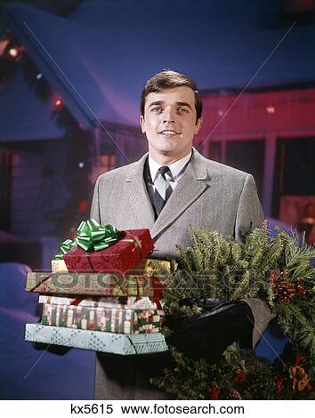 1960 1960S 1970S 1970 Smiling Man Hold Wrapped Presents Gifts & Pine Wreath Front House Decorated Holiday Lights View Large Photo Image Stock Photography - 1960 1960S 1970S 1970 Smiling Man Hold Wrapped Presents Gifts & Pine Wreath Front House Decorated Holiday Lights. Fotosearch