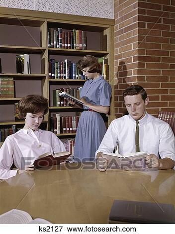 1960 1960S 3 Students Boy 2 Girls In Library Reading Study Studying High School Education Retro Shelves Books View Large Photo Image Stock Photo - 1960 1960S 3 Students Boy 2 Girls In Library Reading Study Studying High School Education Retro Shelves Books . Fotosearch
