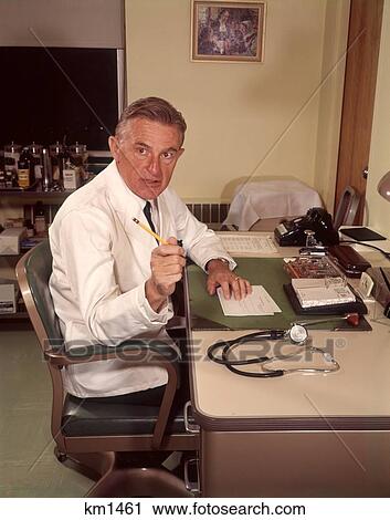 1960 1960S Doctor Pointing With Pencil Seated At Desk In Office Doctors View Large Photo Image Stock Image - 1960 1960S Doctor Pointing With Pencil Seated At Desk In Office Doctors . Fotosearch