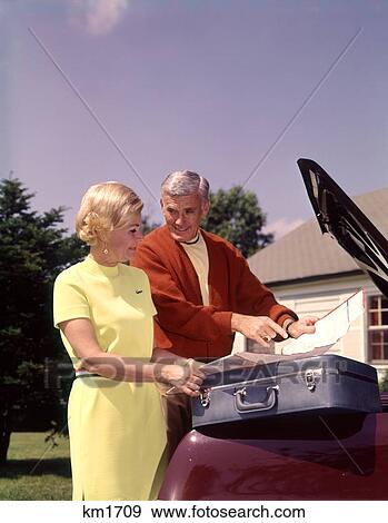 1960 1960S Elderly Senior Couple Load Suitcases In Car Trunk Looking At Map Travel Vacation Road Trip View Large Photo Image Stock Photo - 1960 1960S Elderly Senior Couple Load Suitcases In Car Trunk Looking At Map Travel Vacation Road Trip . Fotosearch