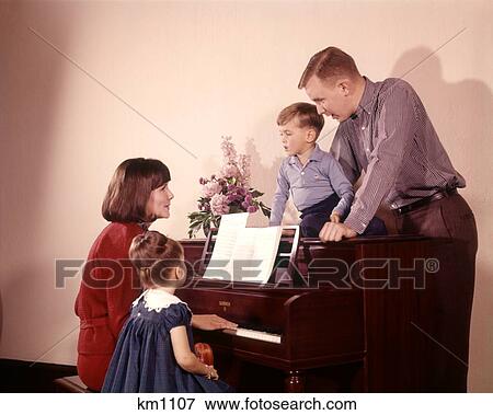 1960 1960S Family Singing Around Piano Mother Playing Music Seated On Bench With Daughter Girl Son Boy On Piano View Large Photo Image Stock Photo - 1960 1960S Family Singing Around Piano Mother Playing Music Seated On Bench With Daughter Girl Son Boy On Piano . Fotosearch