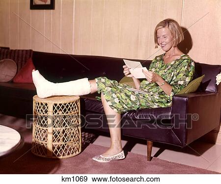 1960 1960S Smiling Woman Leg Broken In Cast On Stool Sitting Leather Sofa Opening Insurance Check View Large Photo Image Stock Photo - 1960 1960S Smiling Woman Leg Broken In Cast On Stool Sitting Leather Sofa Opening Insurance Check . Fotosearch