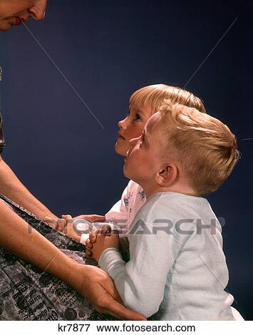 1960 1960S Two Children Boy Girl Kneel Kneeling Mothers Lap Saying Prayers Looking Up Family Religion View Large Photo Image Stock Photo - 1960 1960S Two Children Boy Girl Kneel Kneeling Mothers Lap Saying Prayers Looking Up Family Religion . Fotosearch