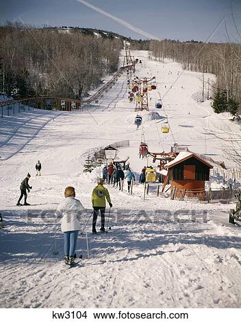 1960S 1960 Group Of People Men Women At Bottom Of Slope Going To Get On Ski Lift Skis Skiing Mountain Resort Retro View Large Photo Image Picture - 1960S 1960 Group Of People Men Women At Bottom Of Slope Going To Get On Ski Lift Skis Skiing Mountain Resort Retro. Fotosearch