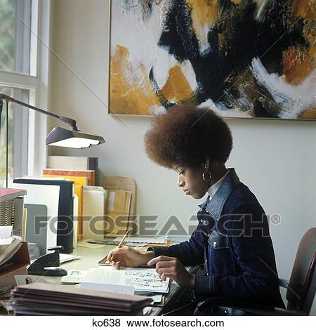 1960S 1970S African-American Woman Sit At Desk Write On Papers By Window Afro Hair Denim Jacket Secretary Student View Large Photo Image Stock Photo - 1960S 1970S African-American Woman Sit At Desk Write On Papers By Window Afro Hair Denim Jacket Secretary Student. Fotosearch