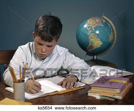 1960S 1970S Boy Doing Homework At Desk Writing Notebook Books Globe View Large Photo Image Picture - 1960S 1970S Boy Doing Homework At Desk Writing Notebook Books Globe . Fotosearch