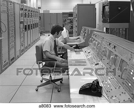 Stock Image - 1960S 1970S Computer Room Mission Mission Control Center Houston Texas 2 Men Sitting At Console . Fotosearch