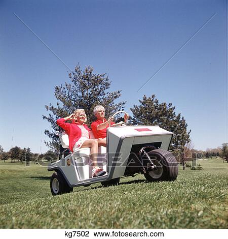 Stock Image - 1960S 1970S Couple In Golf Cart Man Driving Cart Through Golf Course. Fotosearch