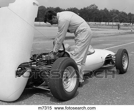 Stock Photography - 1960S 1970S Man Mechanic Driver Working On Engine Of Race Car In Pit On Tarmac Lotus Ford. Fotosearch