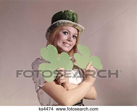 1960S 1970S Retro Irish Woman Smiling Holding Green Shamrocks And Wearing Green Party Hat View Large Photo Image Picture - 1960S 1970S Retro Irish Woman Smiling Holding Green Shamrocks And Wearing Green Party Hat. Fotosearch