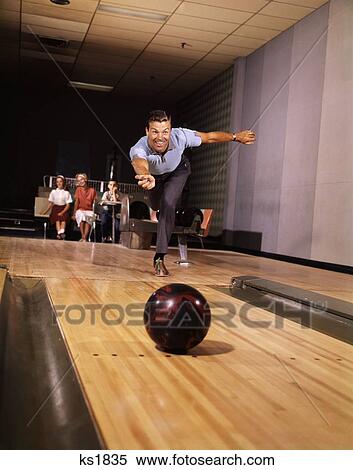 1960S 1970S Smiling Man Throwing Bowling Ball Down Alley As Family Watches In Background Fun Dad Father Retro Vintage View Large Photo Image Stock Photography - 1960S 1970S Smiling Man Throwing Bowling Ball Down Alley As Family Watches In Background Fun Dad Father Retro Vintage. Fotosearch