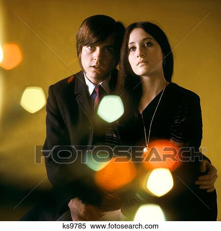 1960S 1970S Young Couple Man Woman Head To Head Dressed In Black Look At Camera Mod Style Serious Expression Blur Lights View Large Photo Image Stock Photography - 1960S 1970S Young Couple Man Woman Head To Head Dressed In Black Look At Camera Mod Style Serious Expression Blur Lights. Fotosearch