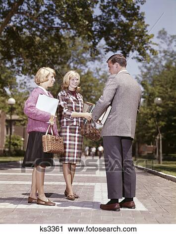 1960S 3 Teens Stand Talk On Campus Walk Boy Wears Suit Girls Coeds Wear Skirts Books Handbags Fashion Flirt Social View Large Photo Image Stock Image - 1960S 3 Teens Stand Talk On Campus Walk Boy Wears Suit Girls Coeds Wear Skirts Books Handbags Fashion Flirt Social. Fotosearch