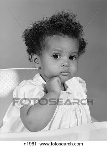 1960S African-American Baby Girl In Dress Sitting In High Chair With Hand On Chin & Serious Expression View Large Photo Image Stock Image - 1960S African-American Baby Girl In Dress Sitting In High Chair With Hand On Chin & Serious Expression . Fotosearch