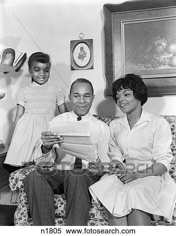 1960S African-American Family On Couch Reading Letter Or Insurance Policy Mother Father Daughter View Large Photo Image Stock Photography - 1960S African-American Family On Couch Reading Letter Or Insurance Policy Mother Father Daughter . Fotosearch
