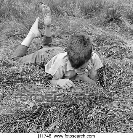 1960S Barefoot Boy Lying Stomach-Down Running Fingers Through High Grass View Large Photo Image Stock Photo - 1960S Barefoot Boy Lying Stomach-Down Running Fingers Through High Grass . Fotosearch