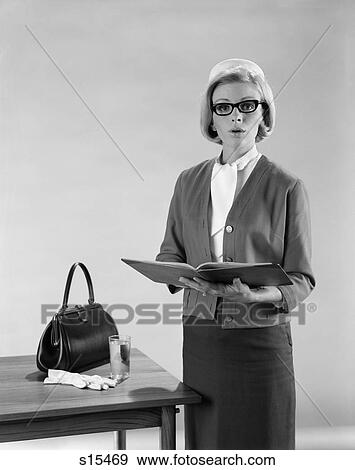 1960S Blonde Woman Speaker Standing By Table Purse Gloves Glass Water Hold Open Book Reading Speech Business Suit Glasses View Large Photo Image Stock Photo - 1960S Blonde Woman Speaker Standing By Table Purse Gloves Glass Water Hold Open Book Reading Speech Business Suit Glasses. Fotosearch