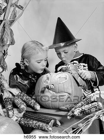 1960S Boy And Girl In Halloween Costumes Looking Into Pumpkin Indoor View Large Photo Image Stock Photography - 1960S Boy And Girl In Halloween Costumes Looking Into Pumpkin Indoor . Fotosearch