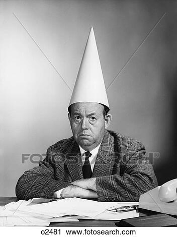 1960S Businessman At Desk Wearing Dunce Cap Facing Camera View Large Photo Image Stock Image - 1960S Businessman At Desk Wearing Dunce Cap Facing Camera . Fotosearch