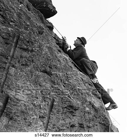 1960S Businessman In Hat & Suit Climbing Rock Holding Rope View Large Photo Image Stock Photo - 1960S Businessman In Hat & Suit Climbing Rock Holding Rope . Fotosearch