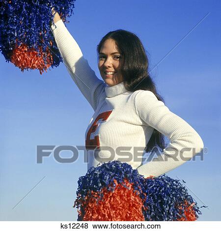 1960S Cheerleader Teen Girl Smiling Big Red E On White Sweater Hold Red & Blue Pompoms One Arm Up Other At Waist View Large Photo Image Stock Photo - 1960S Cheerleader Teen Girl Smiling Big Red E On White Sweater Hold Red & Blue Pompoms One Arm Up Other At Waist. Fotosearch