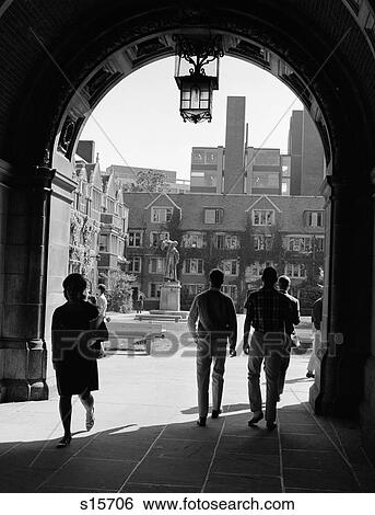 Stock Photograph - 1960S College Students Walking Through Archway In Campus Building With Quadrangle In Background . Fotosearch