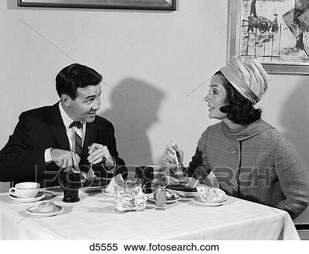 Stock Photography - 1960S Couple Man Woman Eating Meal In Restaurant Woman Wears Turban Style Hat Table Shadow . Fotosearch