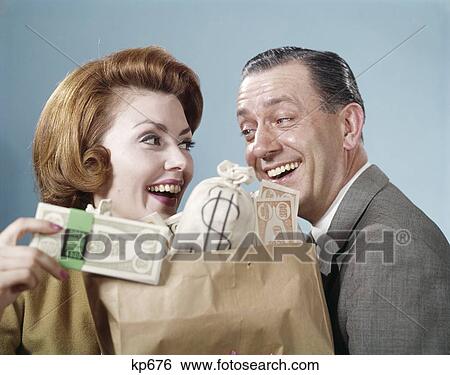 1960S Couple Man Woman Holding Shopping Bag Full Of Money Currency Smiling Happy Wealth Dollars Win Winnings Retro Humor View Large Photo Image Stock Photograph - 1960S Couple Man Woman Holding Shopping Bag Full Of Money Currency Smiling Happy Wealth Dollars Win Winnings Retro Humor . Fotosearch