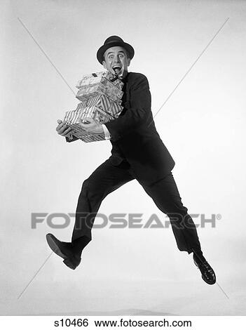 1960S Excited Enthusiastic Man Jumping In Air Running Carrying Pile Presents Gifts Packages View Large Photo Image Stock Photograph - 1960S Excited Enthusiastic Man Jumping In Air Running Carrying Pile Presents Gifts Packages . Fotosearch