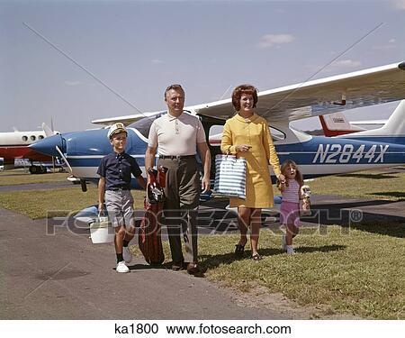 Stock Image - 1960S Family Of Four Walking On Air Field By Propeller Driven Airplanes Man Woman Boy Girl Outdoor . Fotosearch