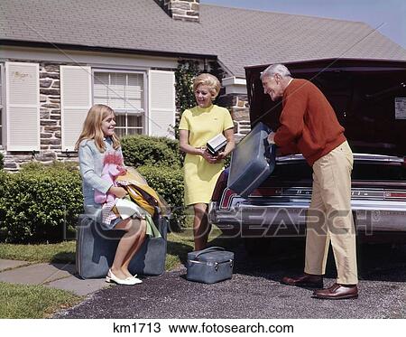 Stock Image - 1960S Family Packing Luggage Into Car For Vacation Or College For Daughter Man Woman Girl Teenage Three Happy . Fotosearch
