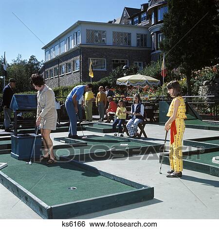 Stock Photograph - 1960S Family Playing Game Of Miniature Golf Mom Dad 3 Kids Summer Vacation Fun Green Putt. Fotosearch