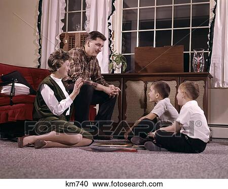 1960S Family With Two Sons Gathered Around Record Player Listening To Music Indoor Living Room Man Woman Boy View Large Photo Image Stock Image - 1960S Family With Two Sons Gathered Around Record Player Listening To Music Indoor Living Room Man Woman Boy . Fotosearch