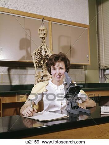 1960S Girl Student White Blouse Notebook Seated At Microscope In Lab Classroom Skeleton Anatomy Pre-Med Nursing Student View Large Photo Image Stock Photo - 1960S Girl Student White Blouse Notebook Seated At Microscope In Lab Classroom Skeleton Anatomy Pre-Med Nursing Student. Fotosearch