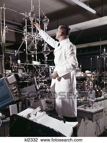 Stock Image - 1960S Laboratory Technician Conducting A Titration Test Science Experiment Elaborate Precision . Fotosearch