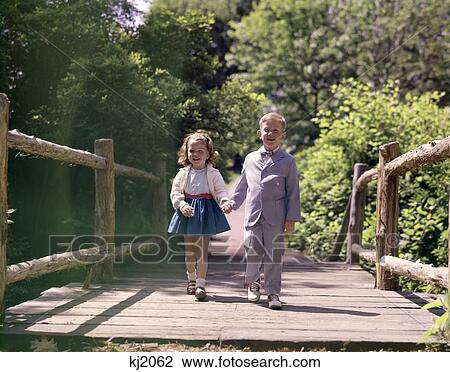 1960S Little Boy And Girl Holding Hands And Walking Across Wooden Footbridge View Large Photo Image Stock Image - 1960S Little Boy And Girl Holding Hands And Walking Across Wooden Footbridge . Fotosearch