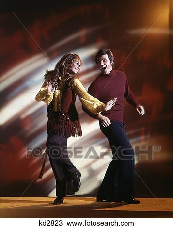 Stock Image - 1960S Man And Woman Dancing In Disco Club Wearing Bell Bottom Pants And Fringed Vest Couple Fun Fad Nostalgia. Fotosearch