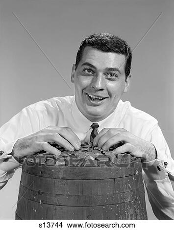 1960S Man Funny Face Expression Smiling Hands On Top Of Barrel Filled With Coins Money Jackpot Finance Win Lottery View Large Photo Image Picture - 1960S Man Funny Face Expression Smiling Hands On Top Of Barrel Filled With Coins Money Jackpot Finance Win Lottery . Fotosearch