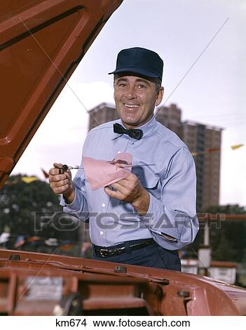 1960S Man Gas Service Station Mechanic Checking Oil Dip Stick Under Car Hood Smiling Retro Blue Uniform Hat Bow Tie View Large Photo Image Picture - 1960S Man Gas Service Station Mechanic Checking Oil Dip Stick Under Car Hood Smiling Retro Blue Uniform Hat Bow Tie . Fotosearch