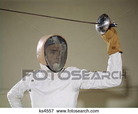1960S Man Holding Foil Sword Epee Above His Head Wearing Helmet Protective Gear Wire Face Mask On Guard Touche Fencing View Large Photo Image Stock Photo - 1960S Man Holding Foil Sword Epee Above His Head Wearing Helmet Protective Gear Wire Face Mask On Guard Touche Fencing. Fotosearch