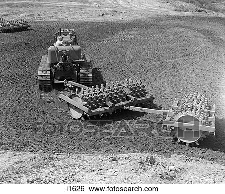1960S Man Operating Grading Machine In Soil Construction Site Heavy Machinery Attachment Roller With Spikes View Large Photo Image Stock Photograph - 1960S Man Operating Grading Machine In Soil Construction Site Heavy Machinery Attachment Roller With Spikes . Fotosearch