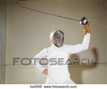 1960S Man Protective Clothing Helmet Wire Face Mask Holding Waving Foil Epee Sword Above Head On Guard Touche Duel View Large Photo Image Stock Photo - 1960S Man Protective Clothing Helmet Wire Face Mask Holding Waving Foil Epee Sword Above Head On Guard Touche Duel . Fotosearch