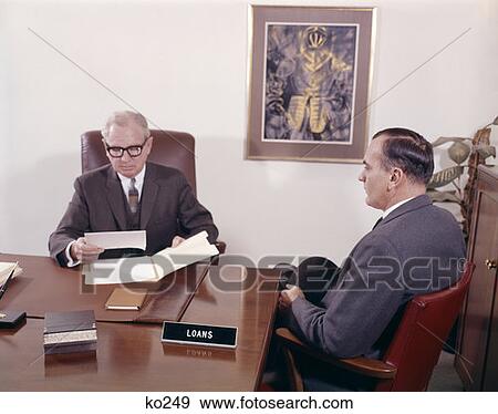 1960S Man Talking To Banker Loan Officer Loans Bank Desk View Large Photo Image Stock Photo - 1960S Man Talking To Banker Loan Officer Loans Bank Desk. Fotosearch